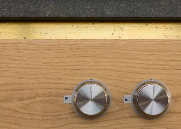 Detail of the kitchen island with integrated Gaggenau induction hob wrapped in Cathedral Oak Veneer, topped with a tooled edge brushed black granite countertop and brass handle strip. Refined kitchen simplicity.